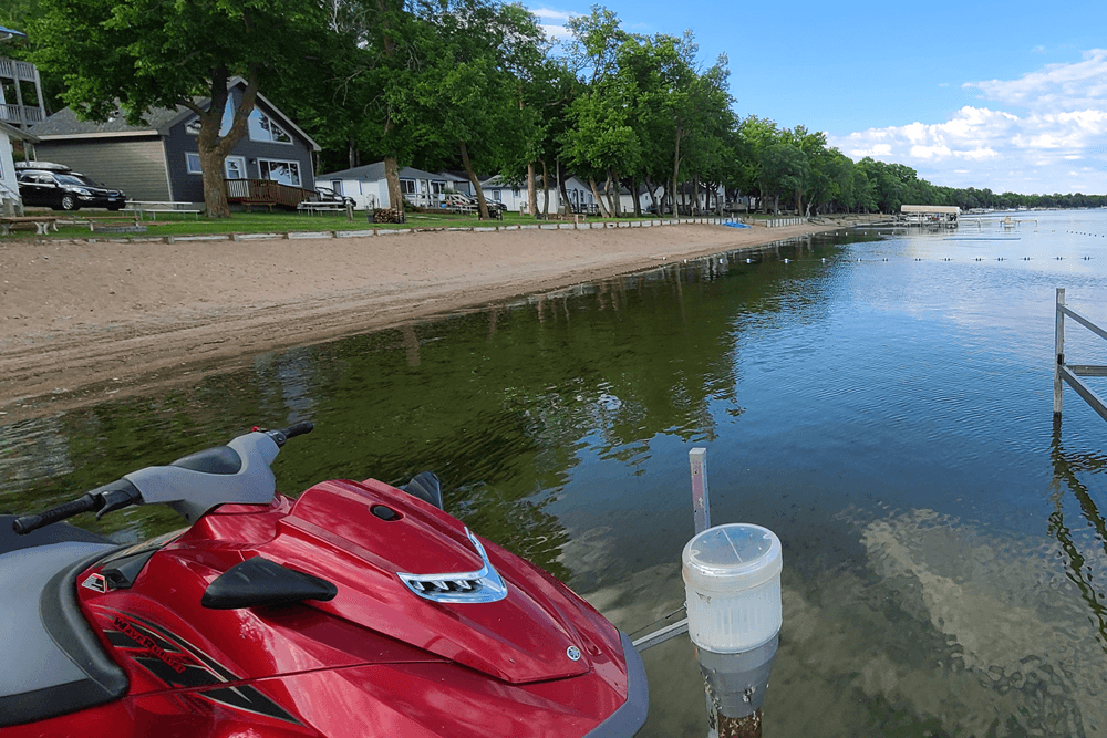 Red jetski tied to doc in water near beach