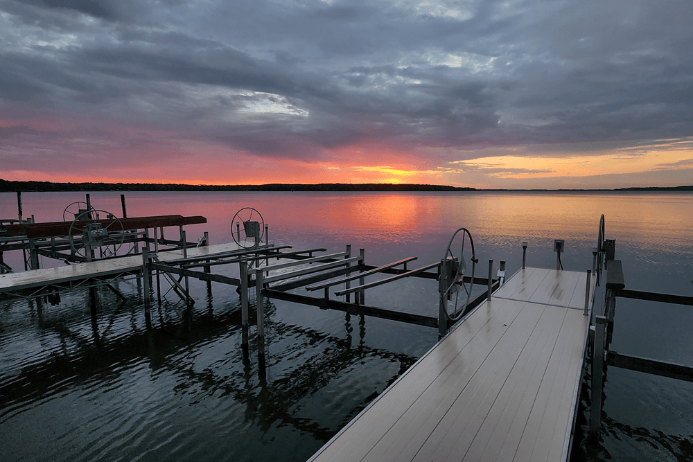 Sun setting over water and empty boat docks in foreground